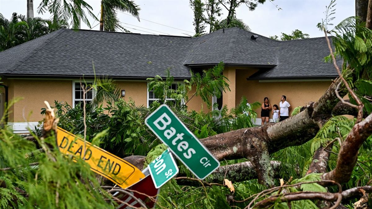 Oscar Garcia and his family stand outside his house after it was hit by a reported tornado in Fort Myers، Florida، during the approach of Hurricane Milton on October 9، 2024.